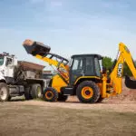 JCB 3CX Backhoe Loader dumping dirt into a dump truck.