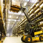 JCB 77-52D diesel teletruk lifting a pallet in a warehouse.