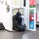 Advance SC4000 ride-on scrubber exiting elevator.