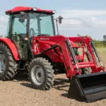 Mahindra 2670 compact utility tractor with cab parked in open dirt and grass field.