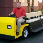 operator driving yellow Columbia Custom Platform utility vehicle with bench feature on bed.