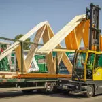 Combilift C12000-4WSL Two Directional Sideloader Forklift carrying large lumber pieces outdoors.