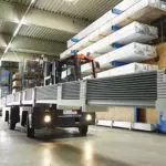 Combilift C12000-4WSL Two Directional Sideloader Forklift hauling material through warehouse.