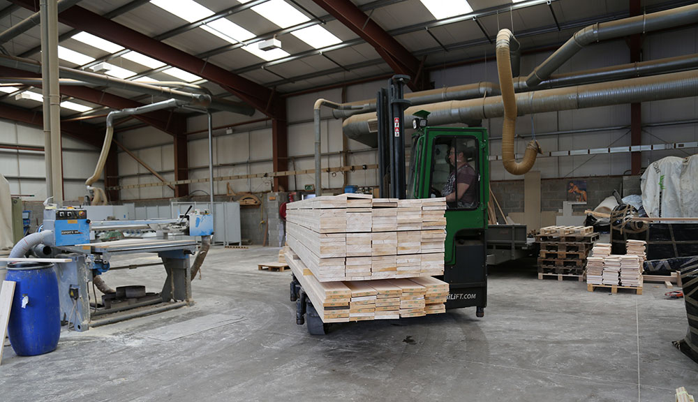 Combilift C Series C6000E electric forklift carrying lumber material.
