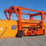 Combilift Combi-SC3 Standard Chain Straddle Carrier getting ready to transport a large container.