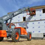 Skyjack SJ843 TH Telehandler lifting pallet of materials into building window.