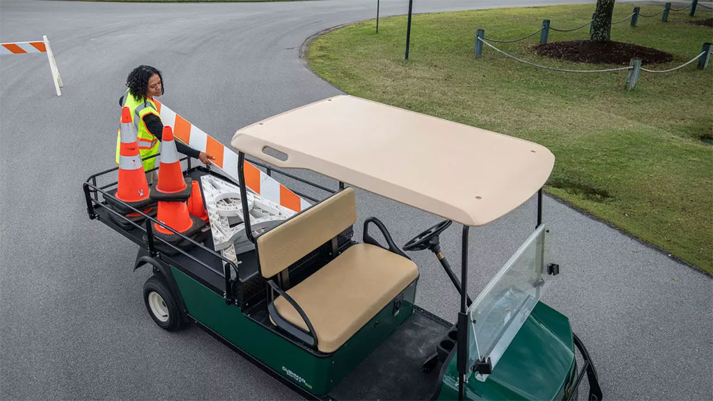 Worker putting materials into Cushman Shuttle 2 Personnel Carrier cargo bed.