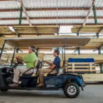Cushman Shuttle 4 personnel vehicle driving people through a lumber yard.