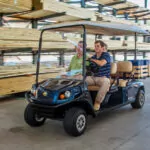 Cushman Shuttle 4 personnel carrier driving through lumber warehouse with personnel.
