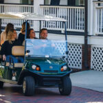 People in Cushman Shuttle 6 personnel vehicle.