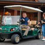 People conversing around Cushman Shuttle 6 personnel carrier.