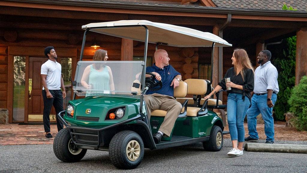 People conversing around Cushman Shuttle 6 personnel carrier.