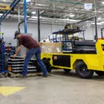 Worker loading Cushman Titan XD burden carrier cargo deck with materials.