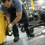 Worker hooking a trailer up to a Cushman Tug 8K tow tractor hitch.