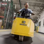 Cushman Tug 8K tow tractor being driven throughout a warehouse.