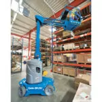 Worker in bucket of Genie GR-27J vertical mast lift reaching top warehouse shelf.