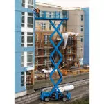 Genie GS-4390 scissor lift raising operator to side of building at jobsite.