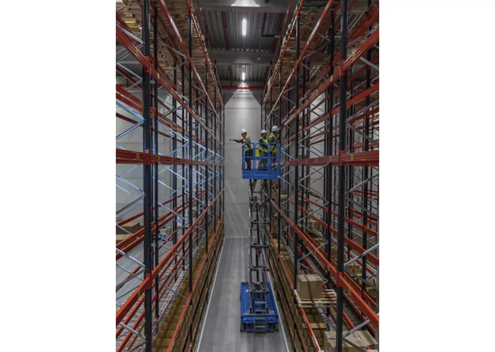 Genie GS-4655 scissor lift in warehouse aisle.