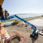 Genie S-85 XC aerial boom lift lifting people on construction site.