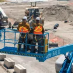 Construction workers in Genie S-85 XC telescopic boom lift bucket.