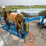 Workers in Genie S-85 XC telescopic boom lift work bucket.