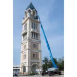 Genie SX-105 XC telescopic boom lift raising workers to the top of a tower.