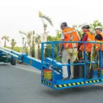 Construction workers in Genie SX-105 XC telescopic boom lift bucket.