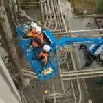 Three construction workers in Genie SX-125 XC boom lift bucket.