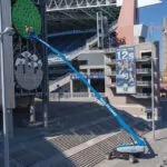 Workers raised in Genie SX-135 XC telescopic boom lift bucket next to a tower.