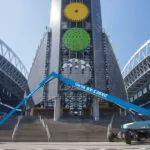 Genie SX-135 XC telescopic boom lift lowering workers in the bucket to the ground.