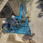 Workers raised in Genie SX-150 aerial boom lift bucket.