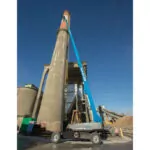 Genie SX-150 aerial telescopic boom lift extended next to tall pillar.