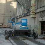 Workers driving Genie SX-150 telescopic boom lift.