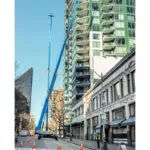 Genie SX-180 telescopic boom lifts raising construction workers to high levels on a tall building.