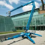 Genie TZ-50 trailer mounted boom lift with worker in bucket.
