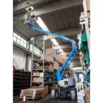 operator in Genie Z-33/18 boom lift replacing warehouse light.