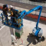 Genie Z-45 XC diesel articulating boom lift raising operator at outdoor work site.