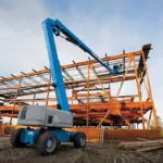 Operator in Genie Z-80/60 boom lift working on building structure.