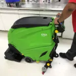 Worker cleaning shop floors with IPC Eagle CT51 walk-behind scrubber.