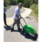 Man sweeping driveway with IPC Eagle SmartVac 464 walk-behind sweeper.