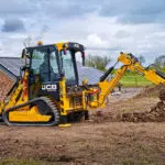 JCB 1CXT Backhoe Loader scooping dirt.