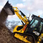JCB 1CXT Backhoe Loader dumping wood chips into large pile.