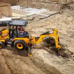 JCB 3CX Backhoe Loader digging hole on construction site.
