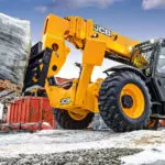 JCB 512-56 Telehandler carrying pallet of materials on construction site.