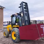 JCB 940 rough terrain forklift lifting materials on a construction site.