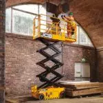 JCB 1930E electric scissor lift lifting operator up to the ceiling in a brick building.