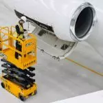 JCB 1930E scissor lift lifting technician up to fix an airplane wing.