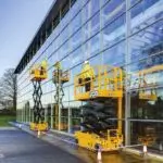 Window washers cleaning outside of glass building on JCB S2632 electric scissor lift.