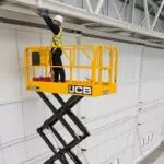 JCB S3246E electric scissor lift holding operator technician repairing a railing.
