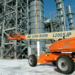 JLG 1200SJP boom lift driving at outdoor facility.